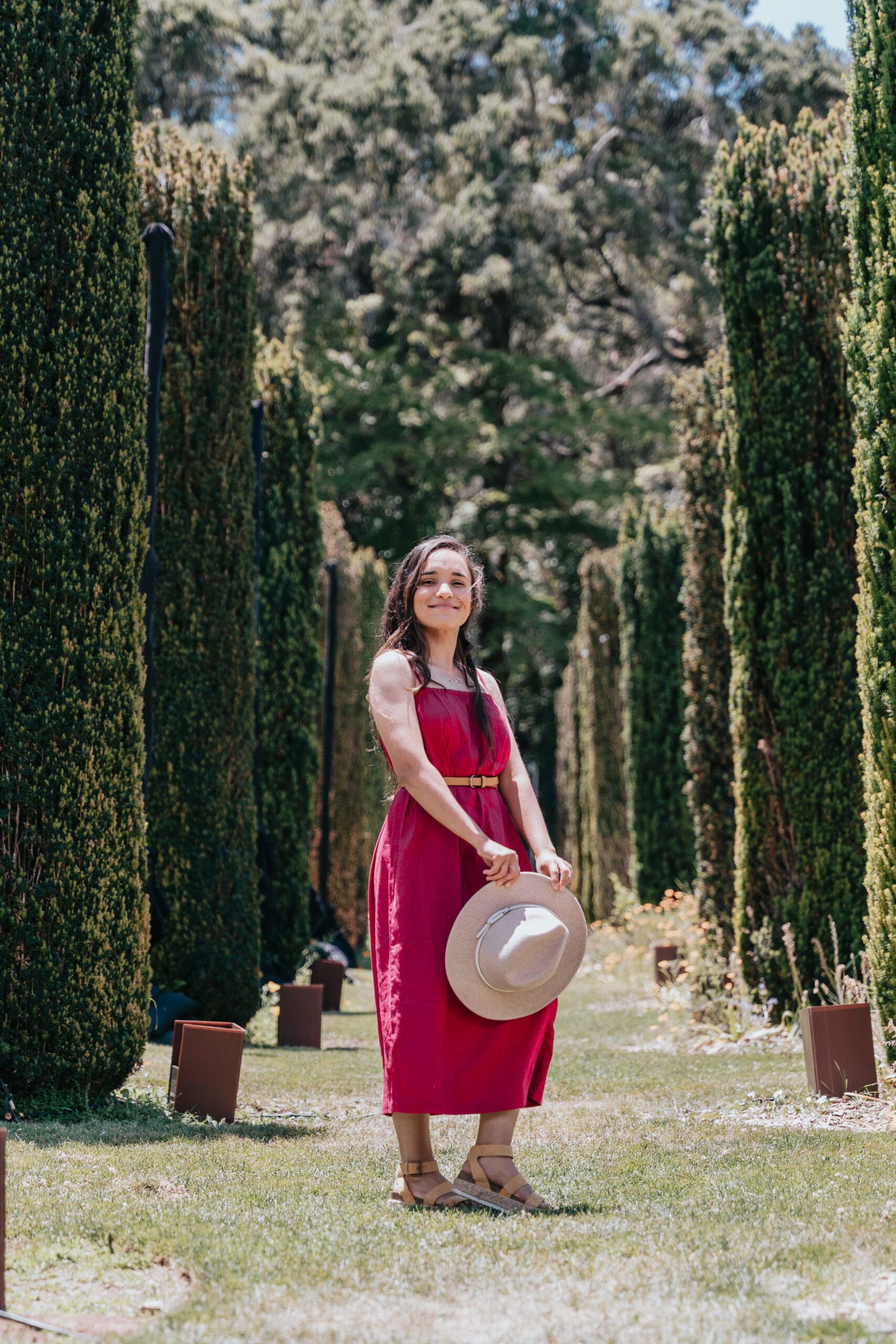 A woman in a red dress posing elegantly in a stunning garden for luxury photography services.